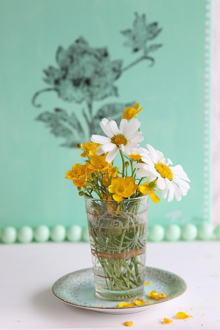 Wiesenblumen im Glas, im Hintergrund Leinwand in grün mit Blumenmuster-Stempeldruck