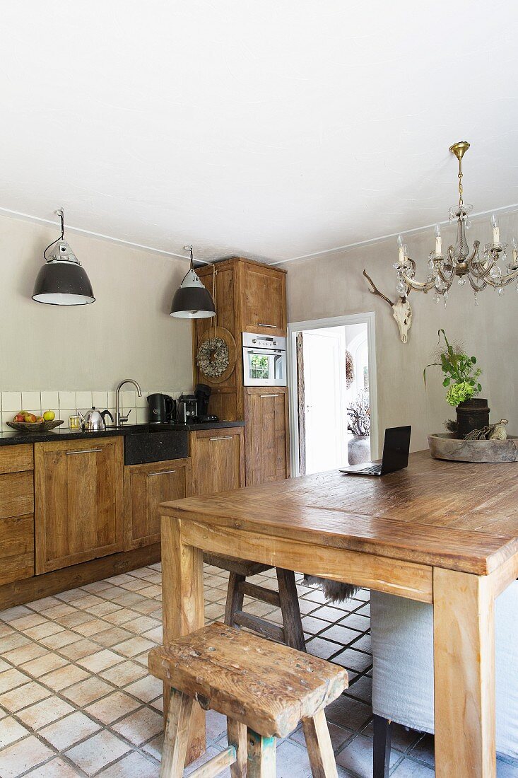 Esstisch und Hocker aus Massivholz, gegenüber Küchenzeile in ländlicher Küche mit Terrakottaboden
