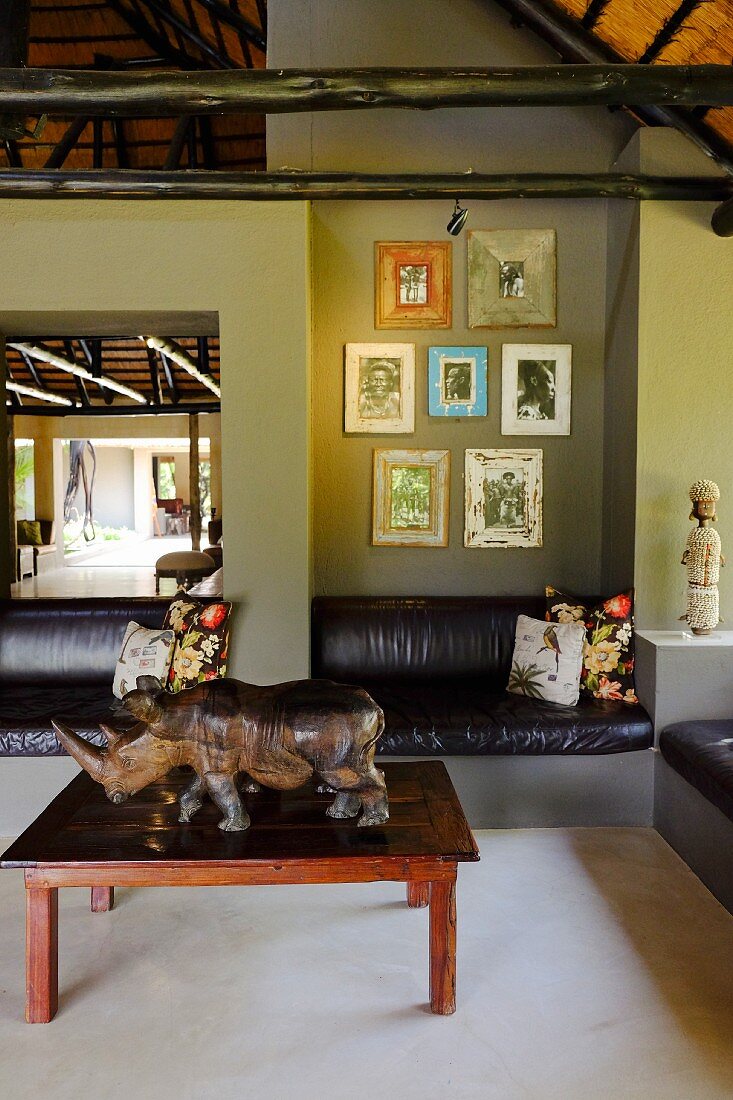 Fitted leather couch along one wall and rhino ornament on coffee table in lounge area with green-painted walls