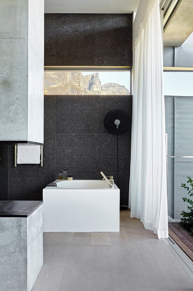 Modern bathroom with open glass wall leading to garden