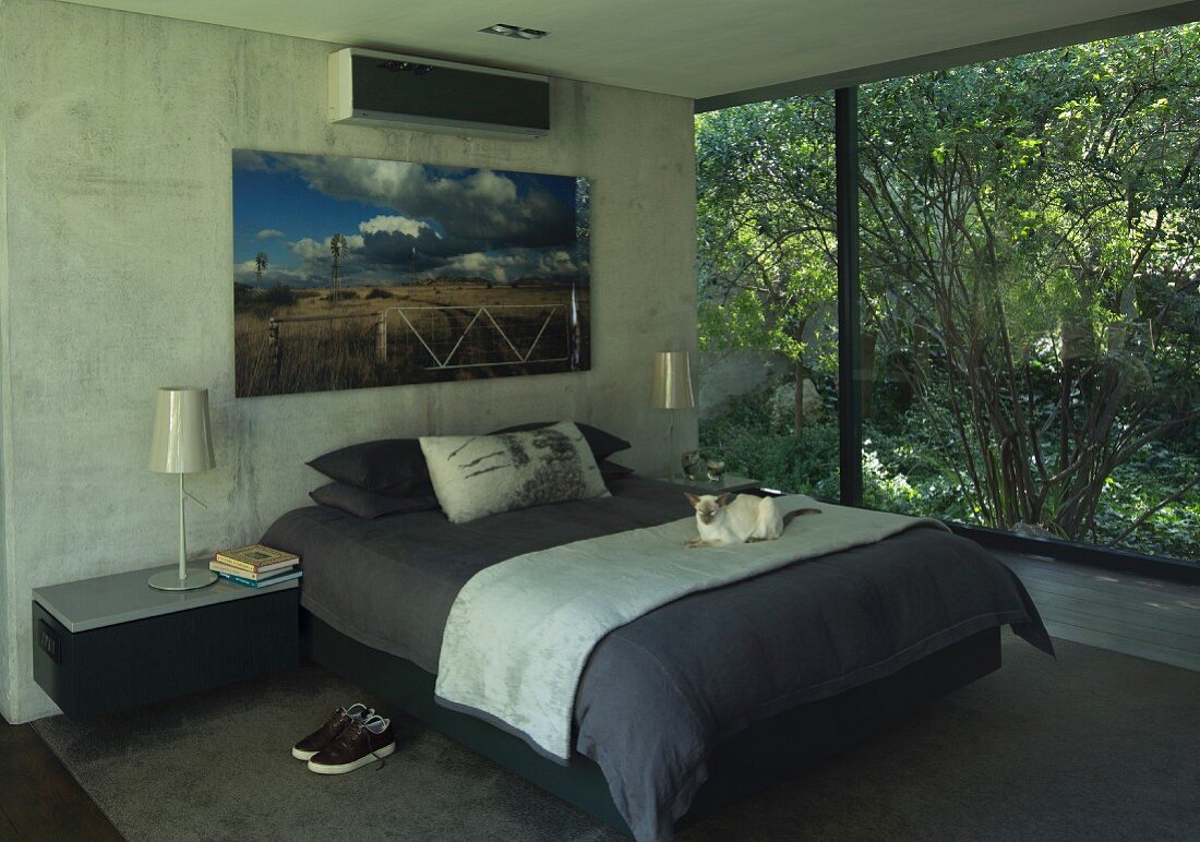 Large artwork above double bed flanked by shimmering, pearl-coloured lamps on bedside cabinets