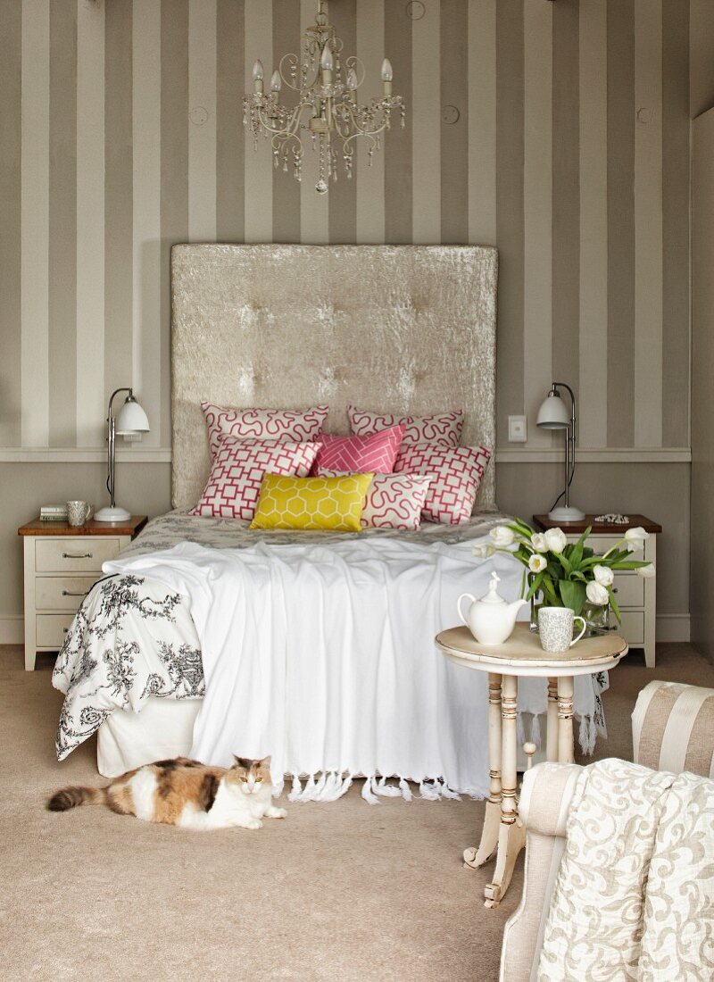 Doppelbett mit geometrisch gemusterten Kissen und hohem Kopfteil in Schlafzimmer mit elegantem Vintage Flair