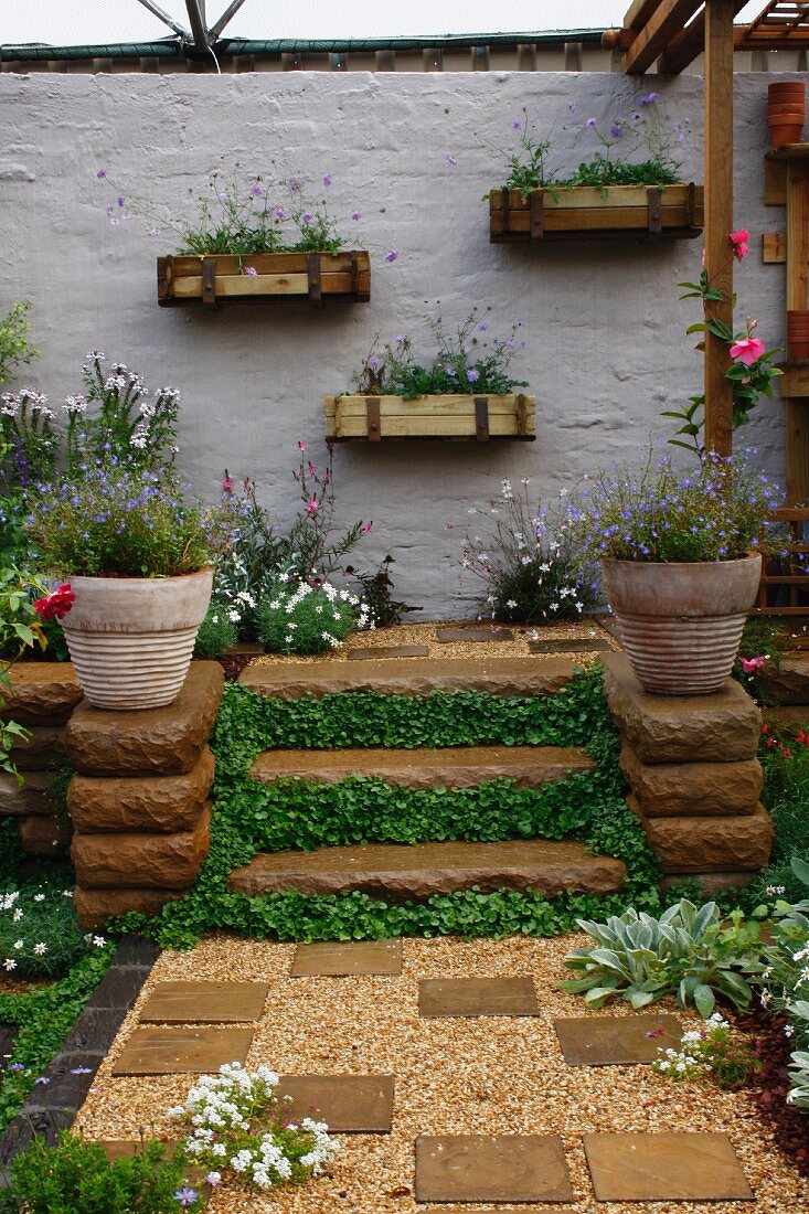 Planted courtyard with steps and wooden planters on wall