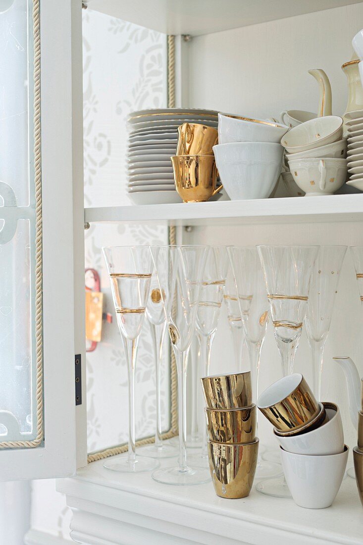 Teller, Tassen und Gläser mit Goldverzierung im Geschirrschrank