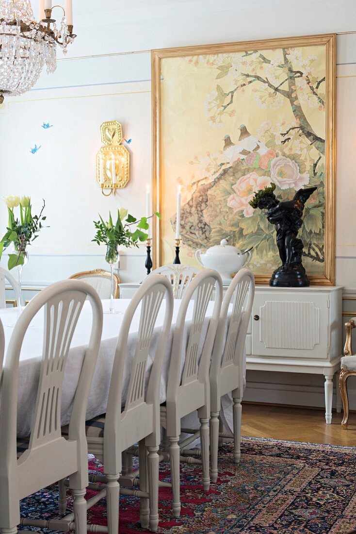 Weiß lackierte Stühle mit gebogenen Rückenlehnen an Esstisch in traditionellem Esszimmer, im Hintergrund Wandgemälde