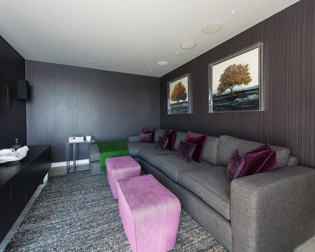 Pinkfarbene Polstertische und graues Sofa in modernem, eleganten Wohnraum, graubraun tapezierte Wände in Streifenoptik