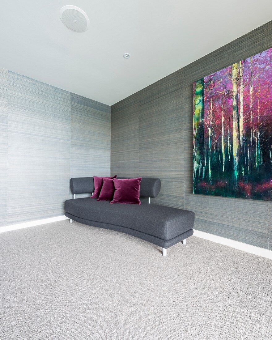 Geschwungenes Sofa mit dunkelgrauem Bezug in Zimmerecke vor tapezierter Wand in graubrauner Streifenoptik