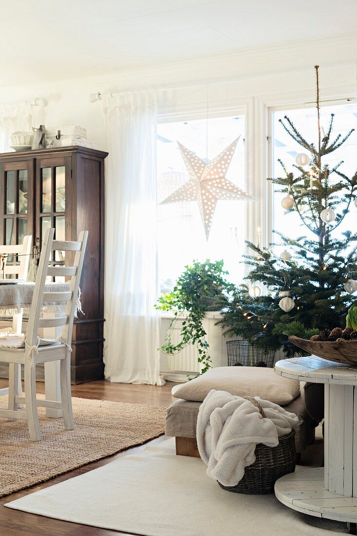 Schlicht geschmückter Weihnachtsbaum neben Kabelrolle und Esstisch