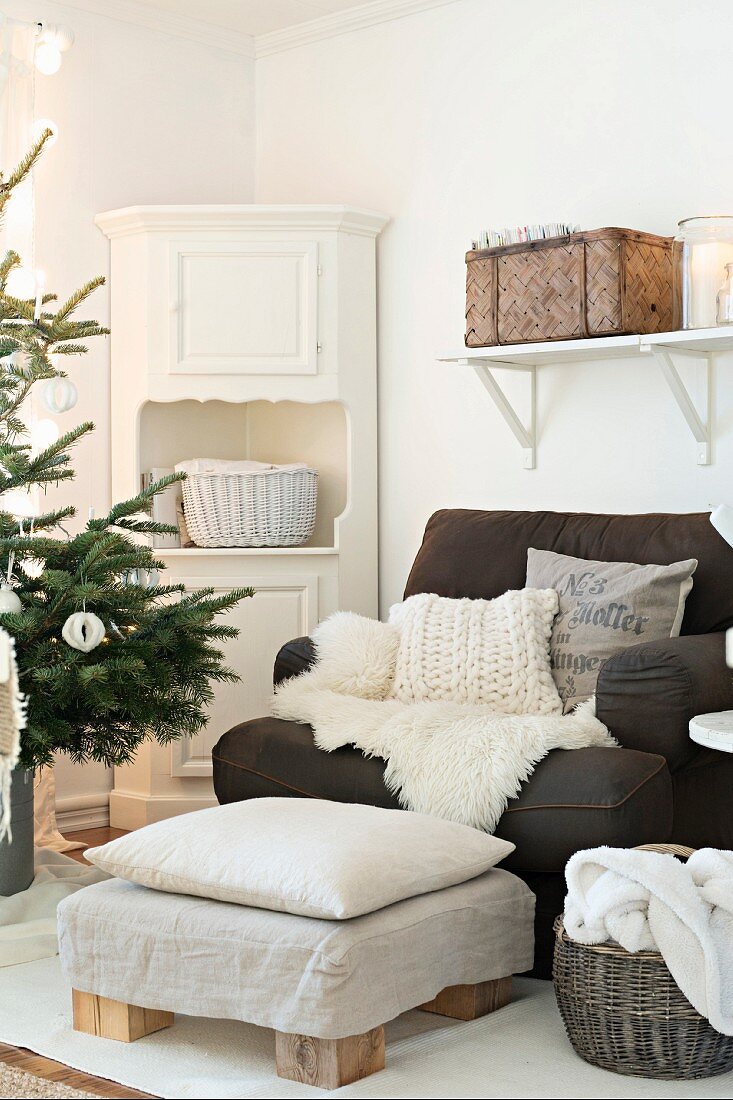 Gemütlicher Sessel mit Fell und Kissen, Fußhocker und Eckschrank, Weihnachtsbaum im Anschnitt