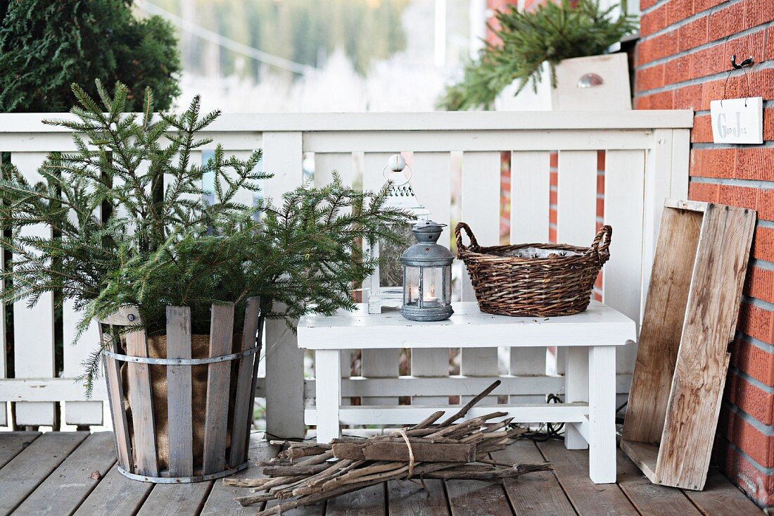 Fir tree in wooden basket next to lantern on bench on veranda