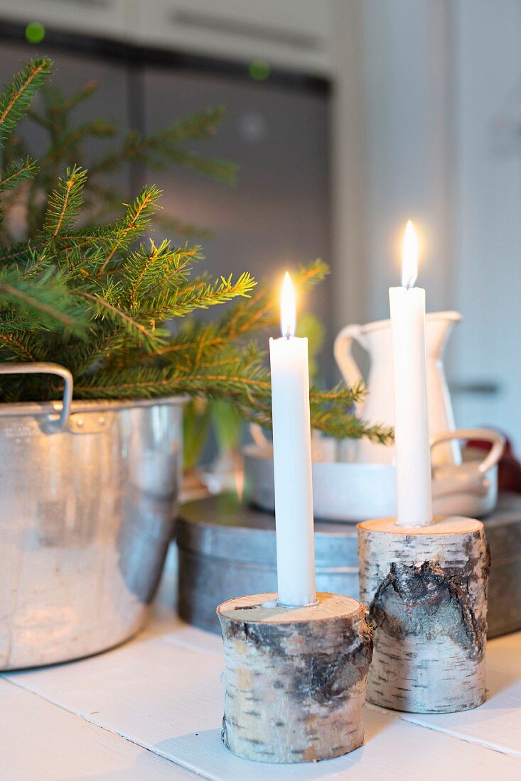 Two lit candles in holders made from birch branches