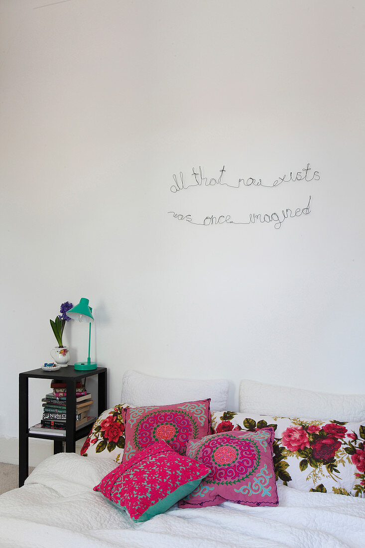 Spruch aus Draht an der Wand überm Bett mit folkloristischen Kissen