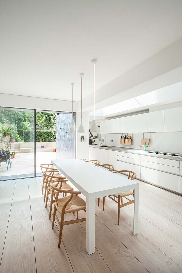 Designer chairs at white dining table next to long kitchen counter