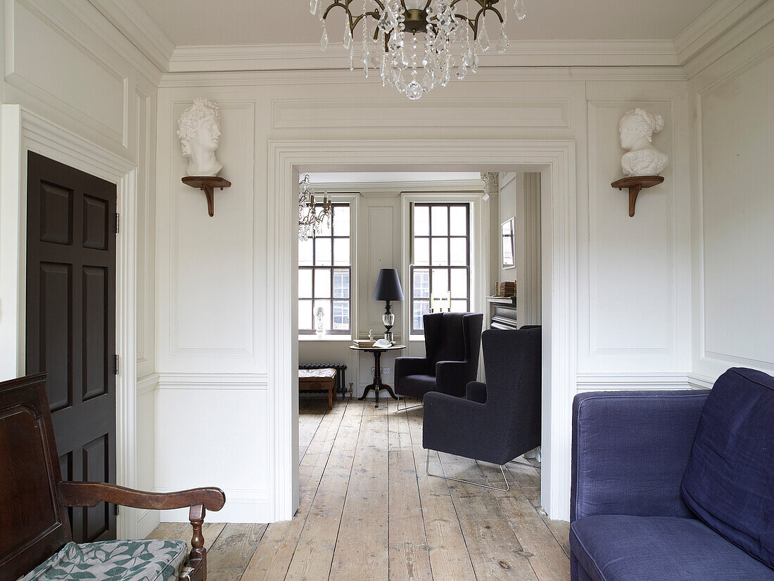 Open doorway flanked by two busts in panelled wall of living room