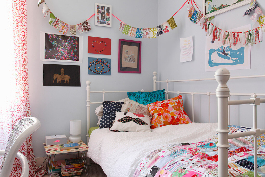 Bunting above metal bed with colourful scatter cushions