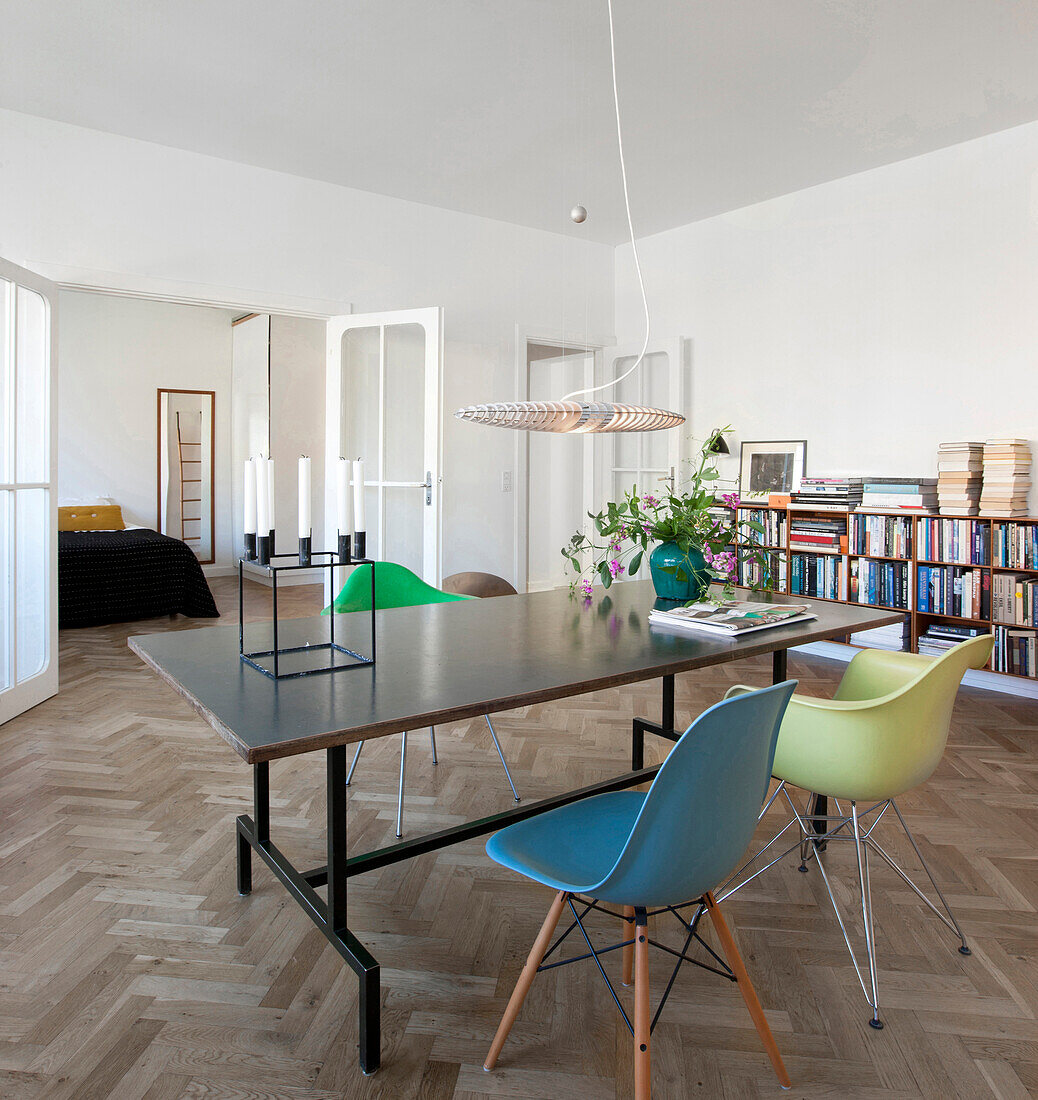 Colourful shell chairs at table in dining room with double doors leading into bedroom