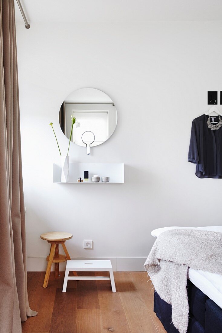 Mimalistische Wandkonsole mit rundem Spiegel darunter Schemel in Schlafzimmer