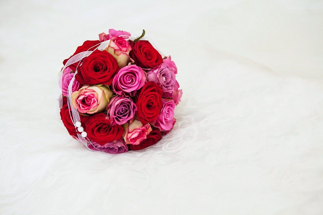 Brautstrauss mit Rosen auf weisser Decke