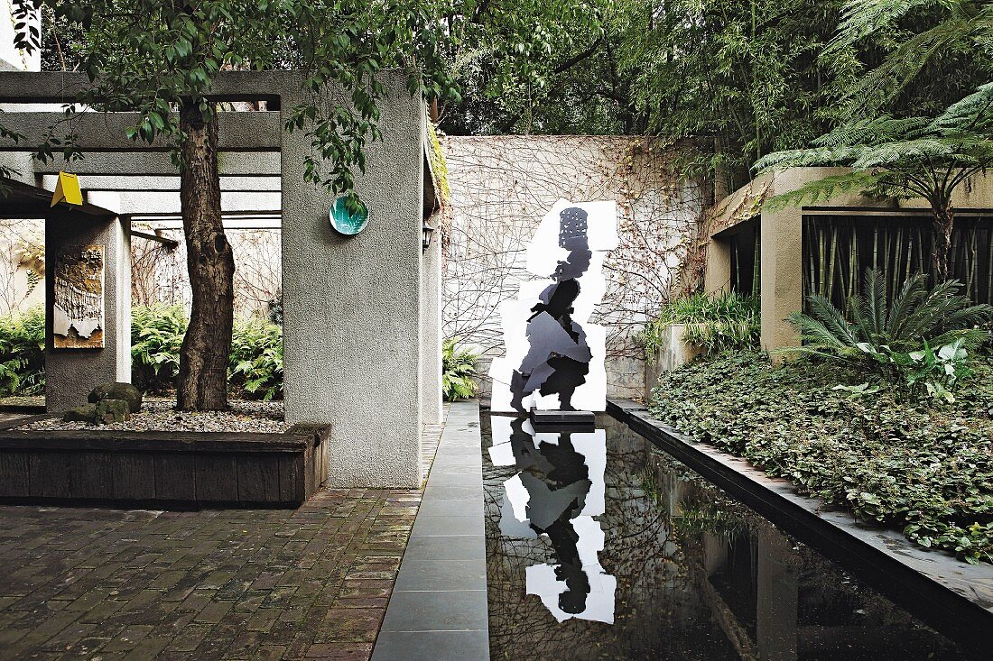Architektonisch gestalteter Garten mit rechteckigem Teich und Kunstwerken
