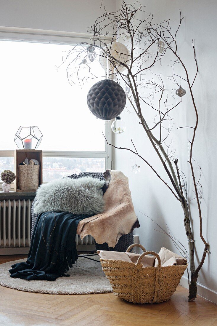 Christmas decorations hung from dried branches attached to wall next to chair and panoramic window