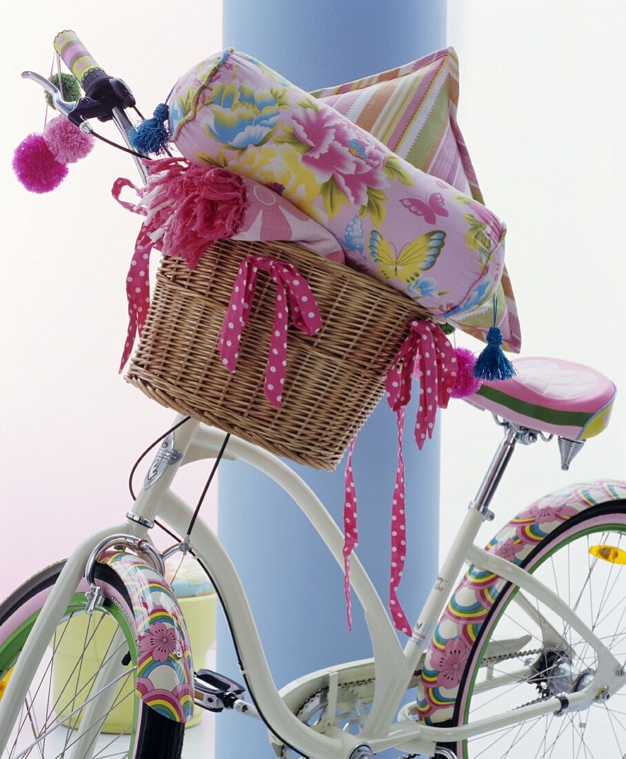 Fahrrad mit verspielten Motiven auf Schutzblechen und Fahrradkorb mit Kissen und Decke