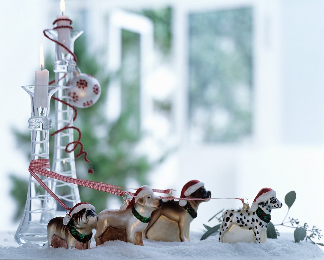 Hundefiguren mit Nikolausmützen und bunten Bändern im Kunstschnee als weihnachtliche Dekoration