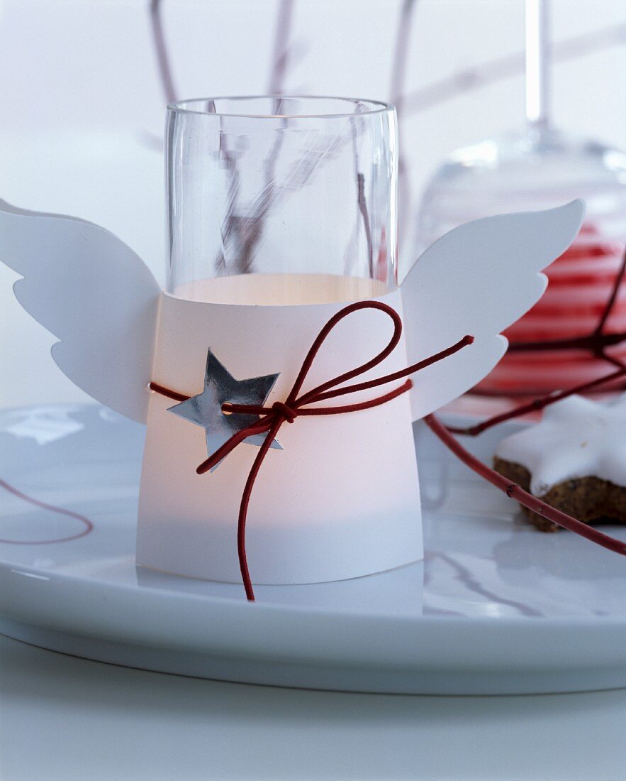 Windlicht dekoriert mit Engelsflügeln als weihnachtliche Tischdekoration