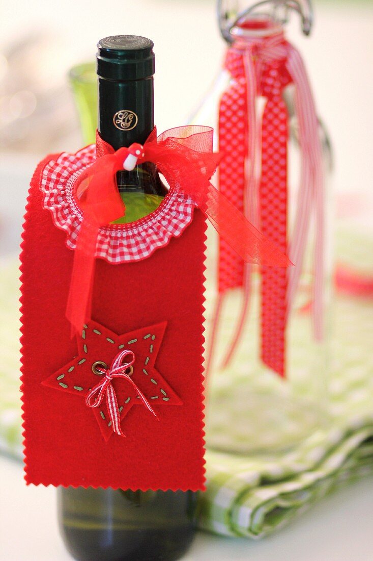 Selbstgebastelte, weihnachtliche Flaschenmanschette aus rotem Filz als Tropfenfänger für Weinflasche