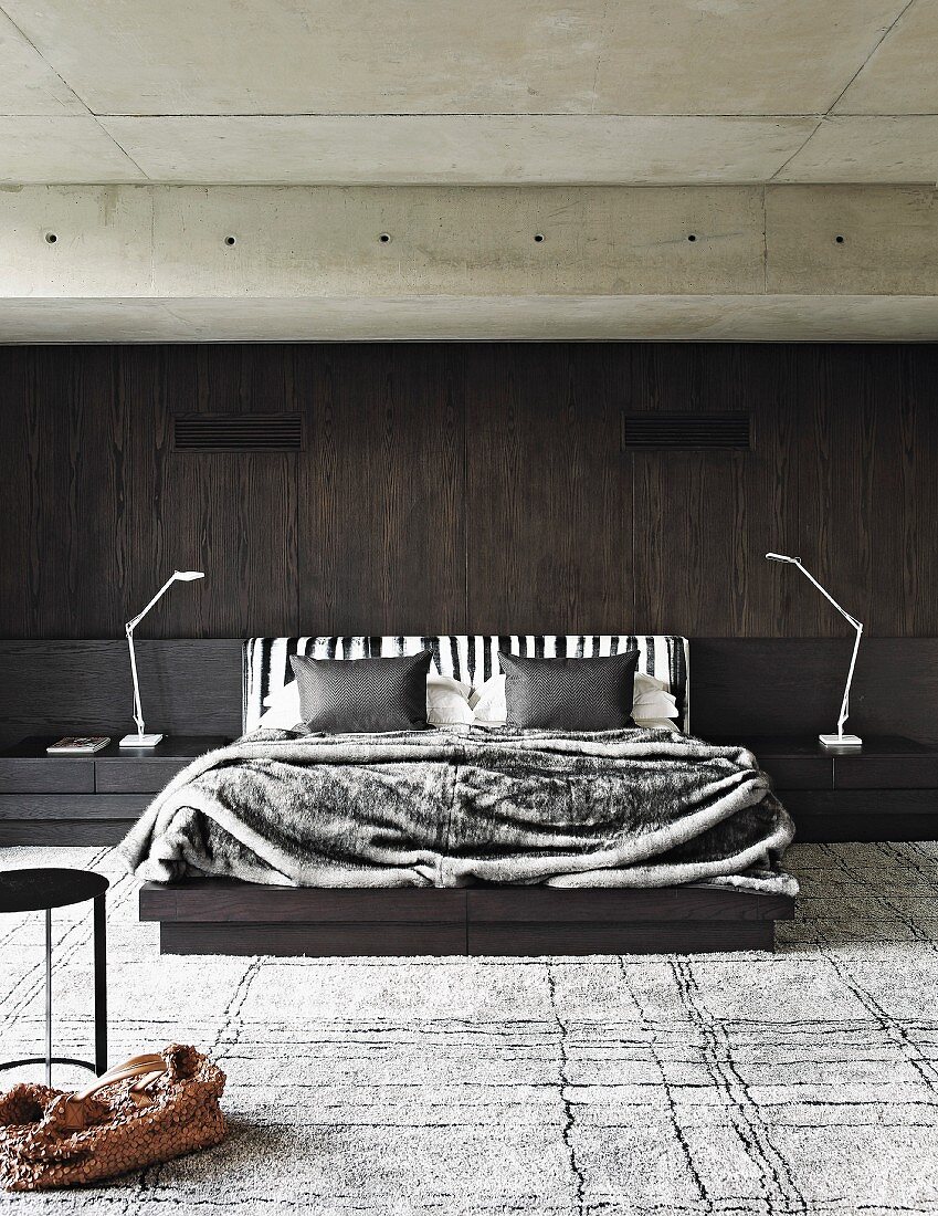 Maskulines Schlafzimmer mit dunkler Holzwand und Betondecke