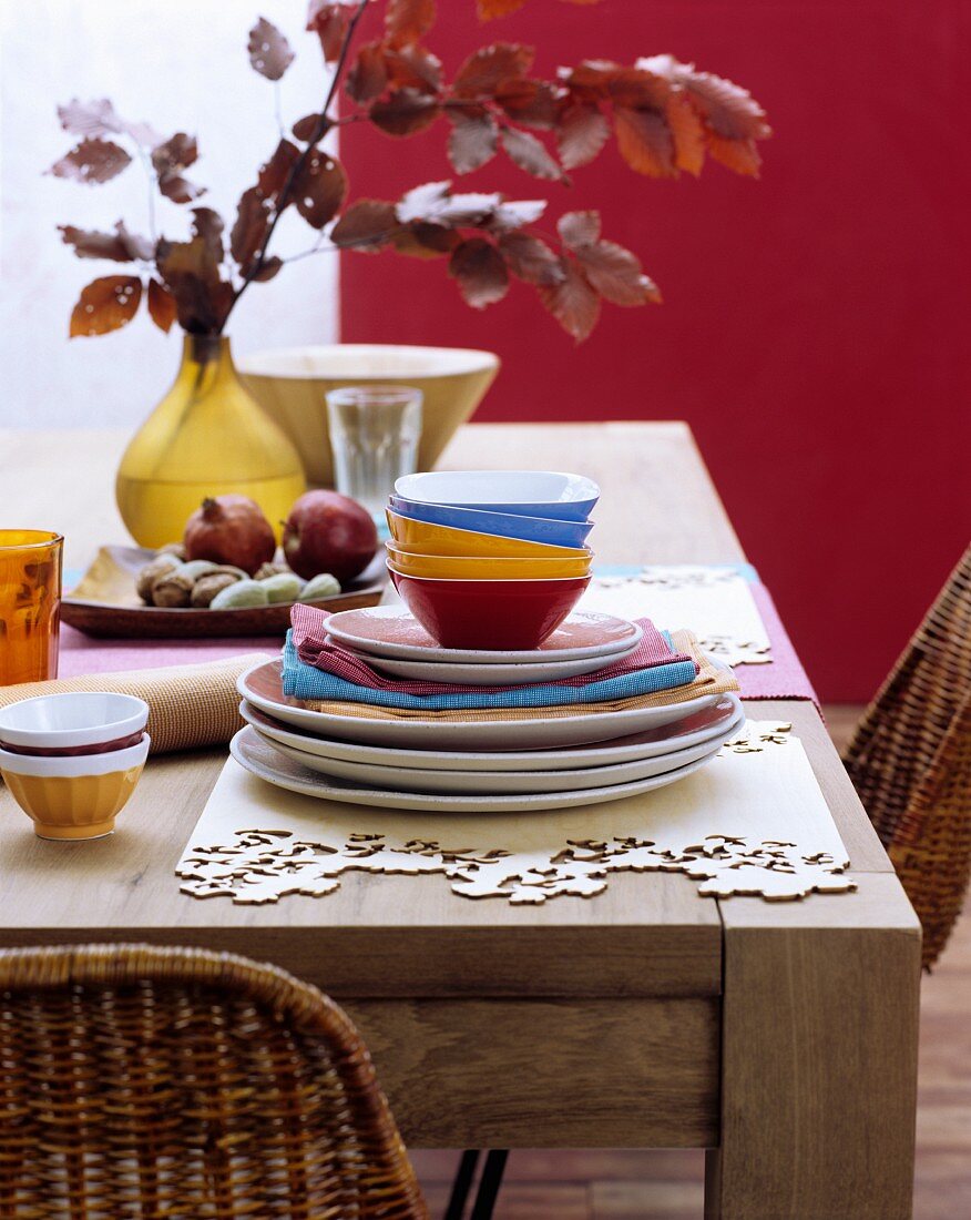 Farbenfrohes Geschirr und handgefertigte Tischsets aus Holzfunier auf rustikalem Holztisch