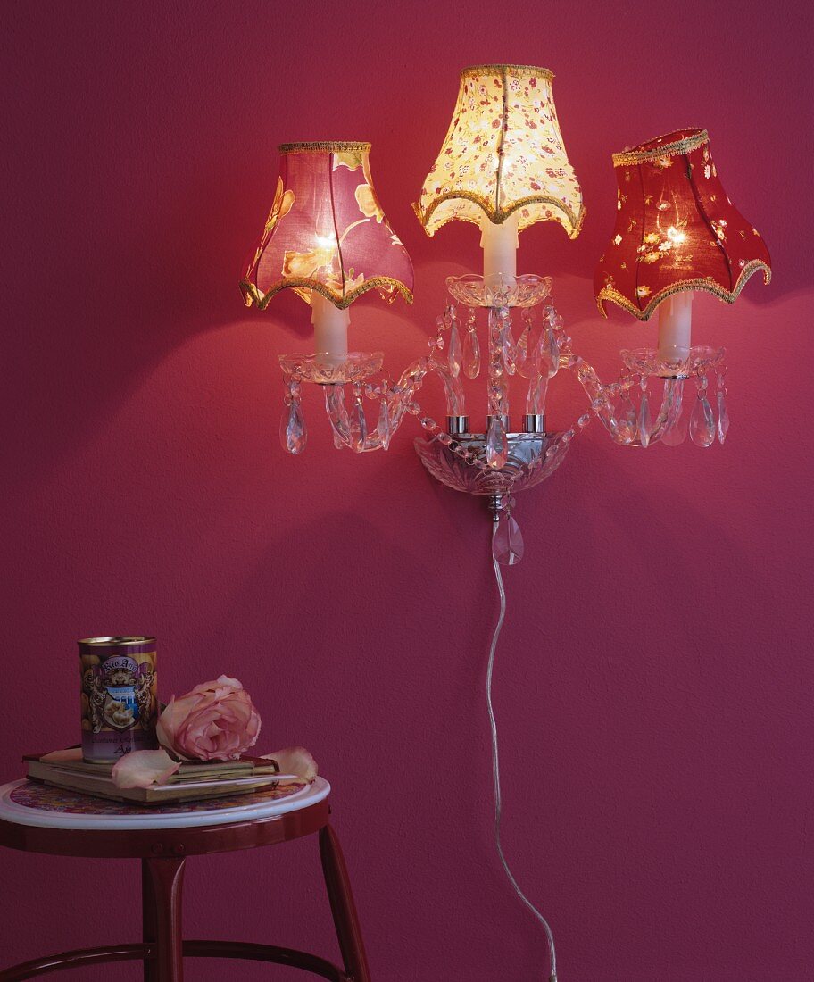 Nostalgische Kristall-Wandleuchte mit Stoffschirmchen an pinkfarbener Wand