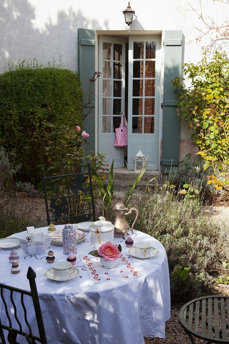 Gedeckter Frühstückstisch in herbstlichem Garten, vor altem Landhaus mit Terrassentür