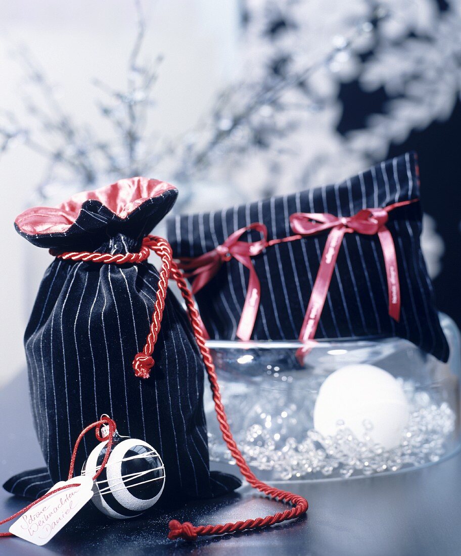 Elegantes Säckchen und Etui aus schwarz-gestreiftem Samtstoff und roten Geschenkbändern