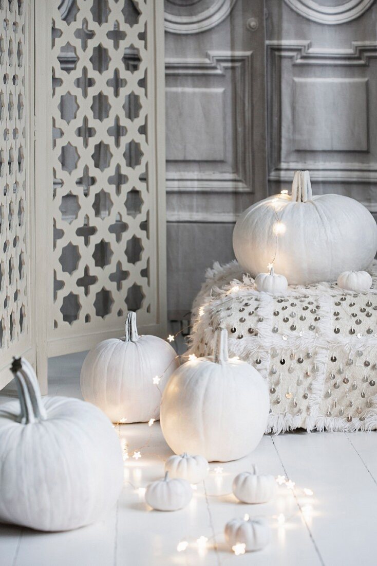 Weiß lasierte Kürbisse mit Lichterkette und Bodenkissen, zu Halloween