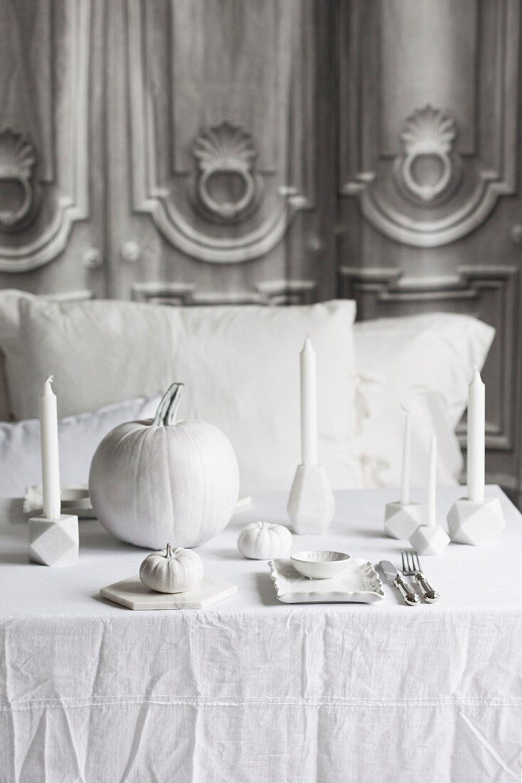 Dekorierter Halloween-Tisch mit Kürbissen und Kerzen in Weiß