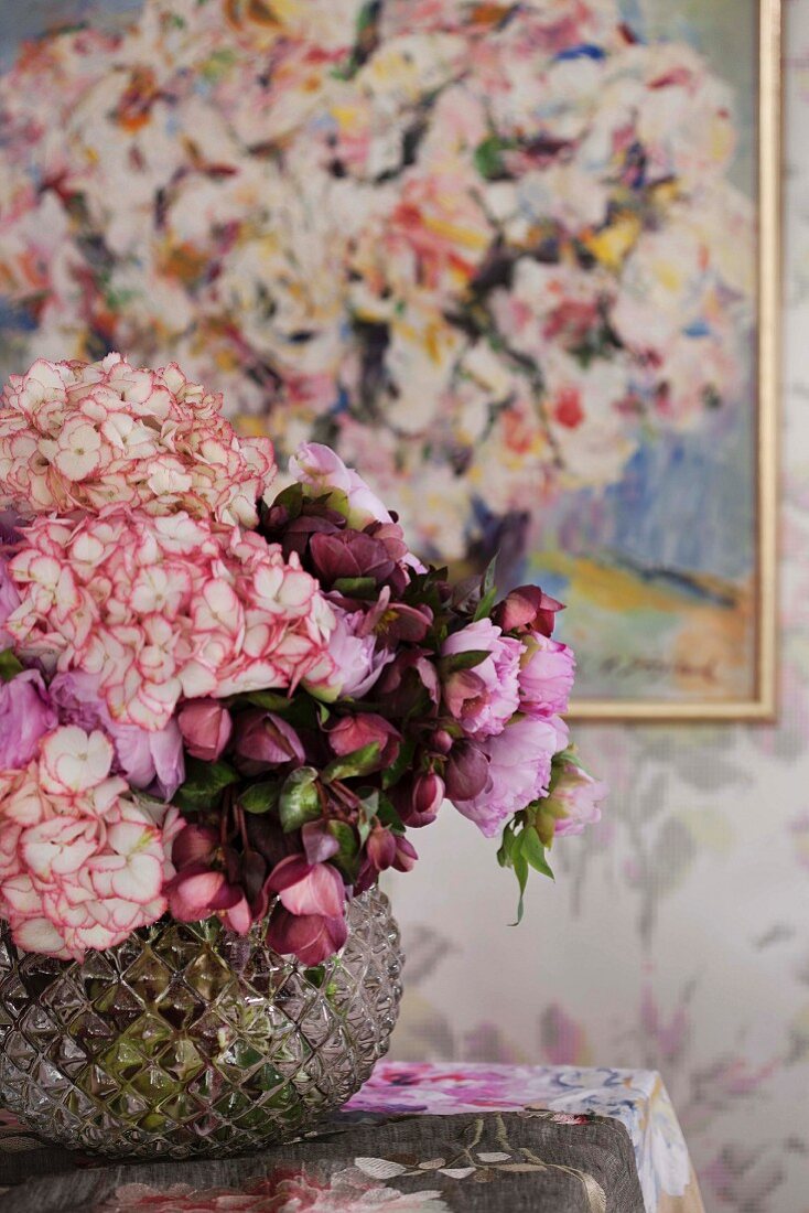 Romantischer Blumenstrauss in Glasvase auf Tisch vor Wandgemälde