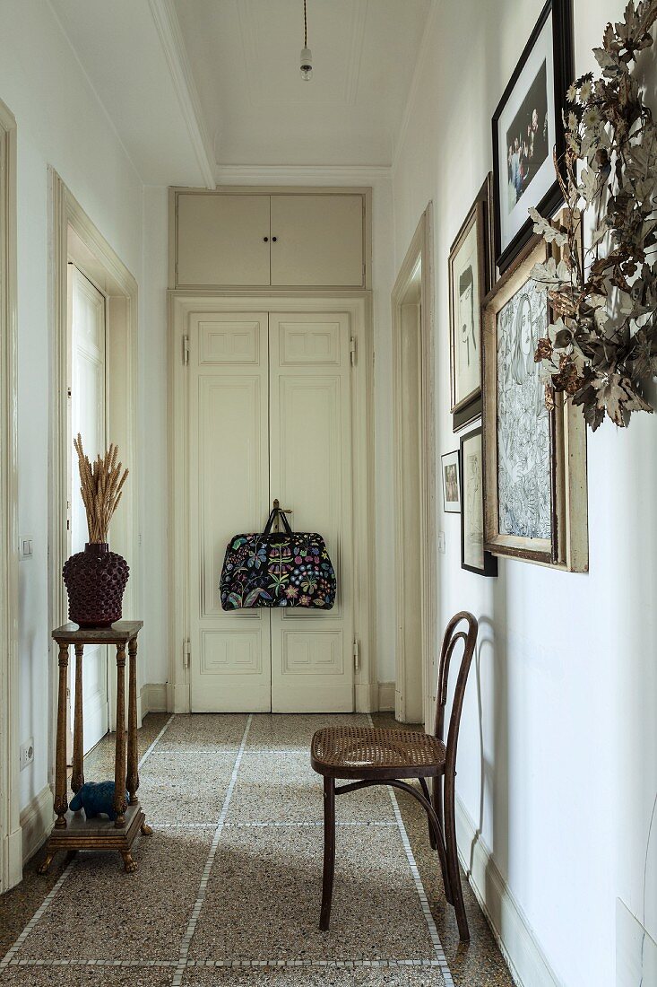 Thonet chair against wall in narrow hallway with terrazzo floor in period apartment