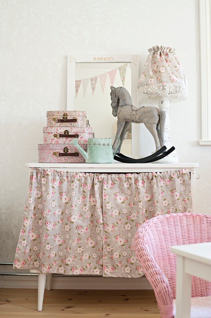 Rocking horse ornament and small cases on dressing table with floral skirt