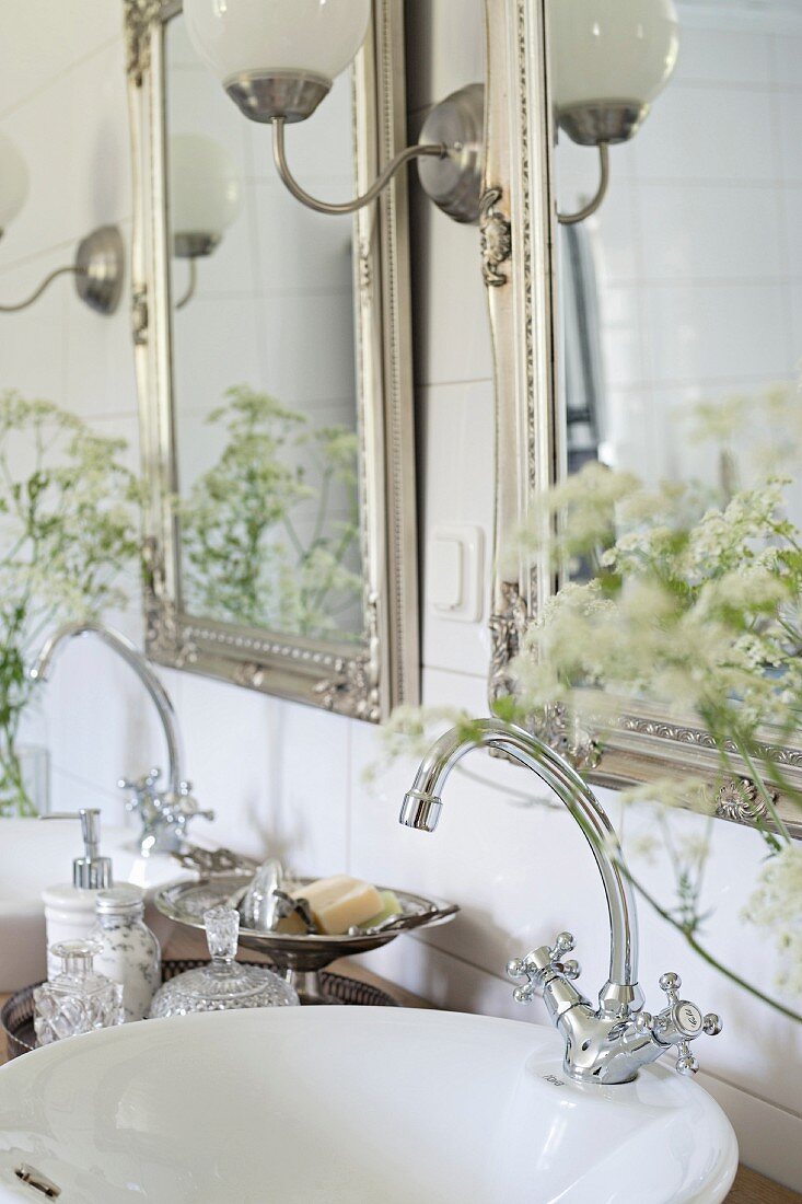 Two silver-framed mirrors above twin sinks with vintage-style tap fittings