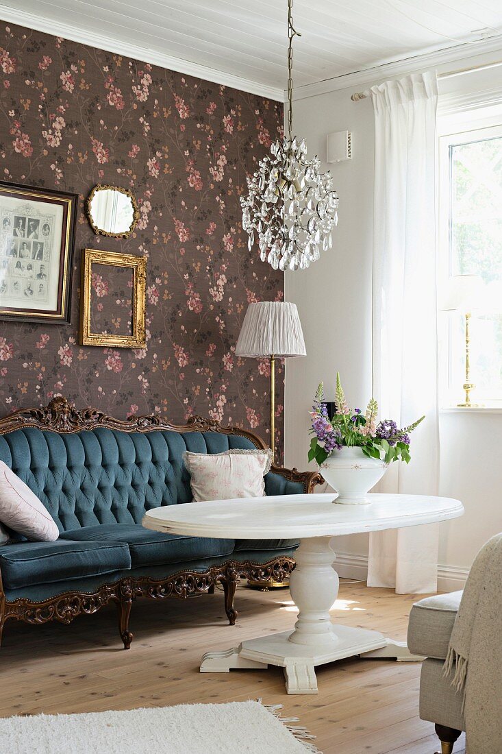 Baroque sofa against floral wallpaper and white coffee table with pedestal base