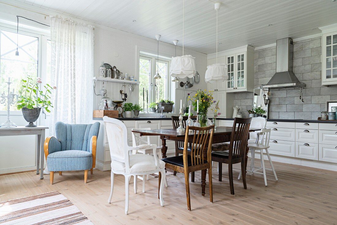 Antiker Holztisch mit verschiedenen Stühlen in großer Landhausküche