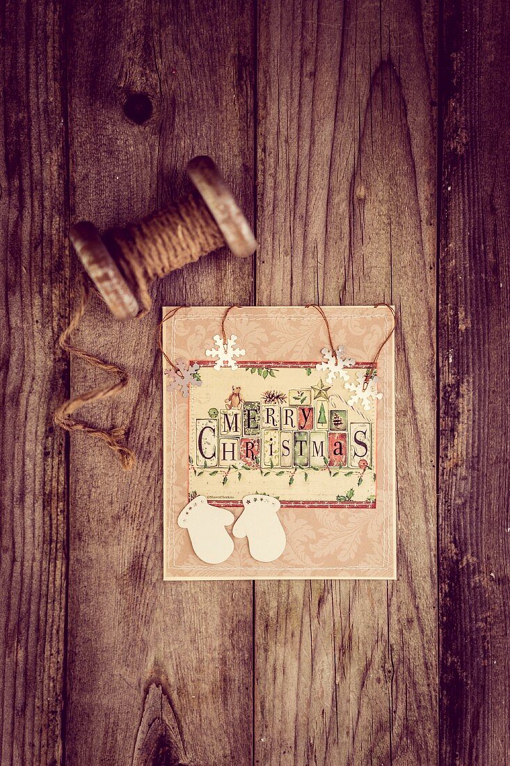 Christmas card and vintage reel of string on rustic wooden surface