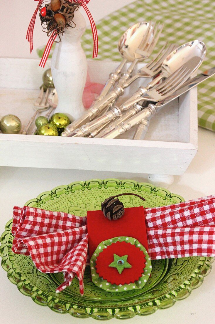 Hand-sewn, red napkin ring with pale green felt star and red and white gingham napkin on green glass plate