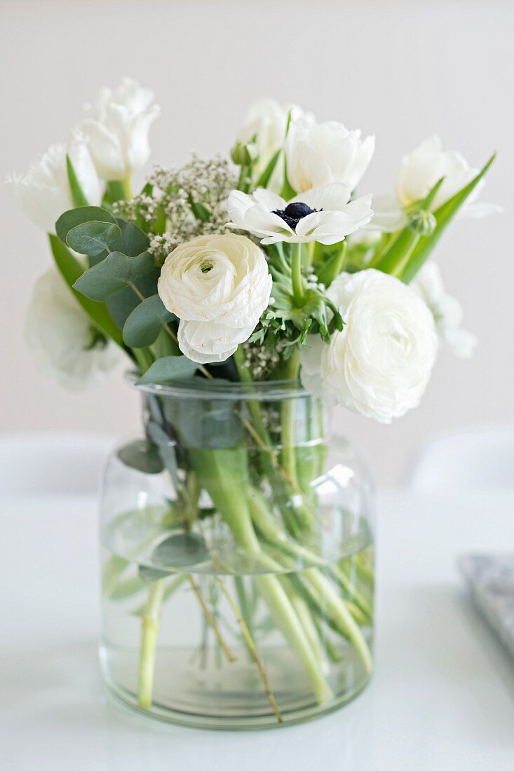 Strauß mit weißen Frühlingsblumen in einer Glasvase
