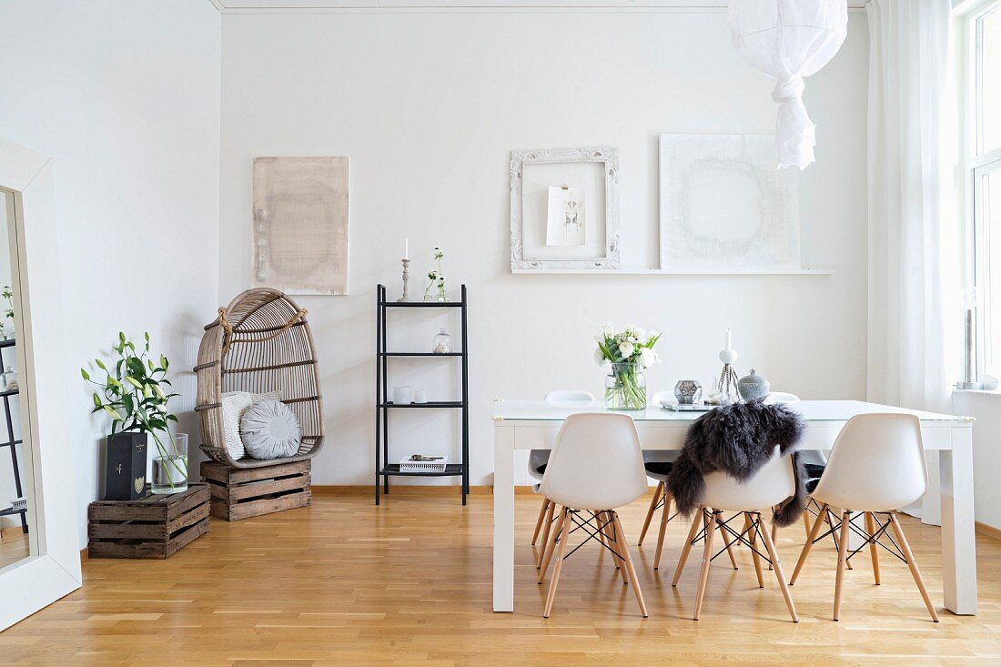 Skandinavisches Esszimmer mit weißen Schalenstühlen und Weinkisten als Deko
