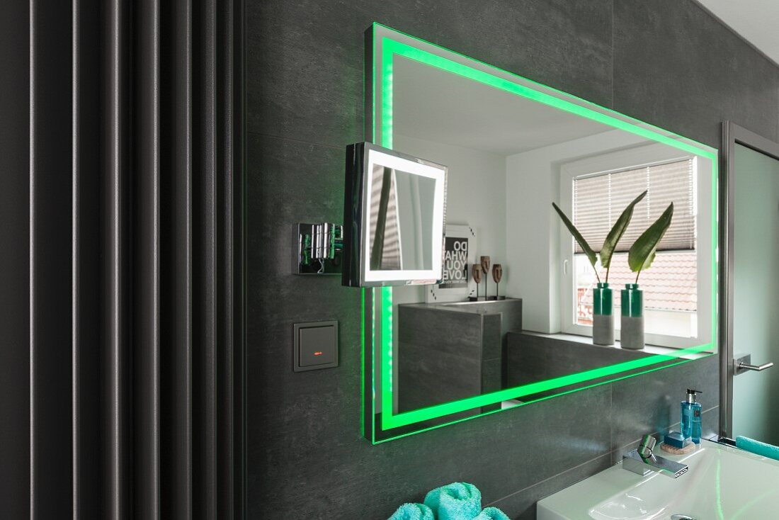 Wandspiegel mit integrierter LED Beleuchtung in Grün, an grau gefliester Wand