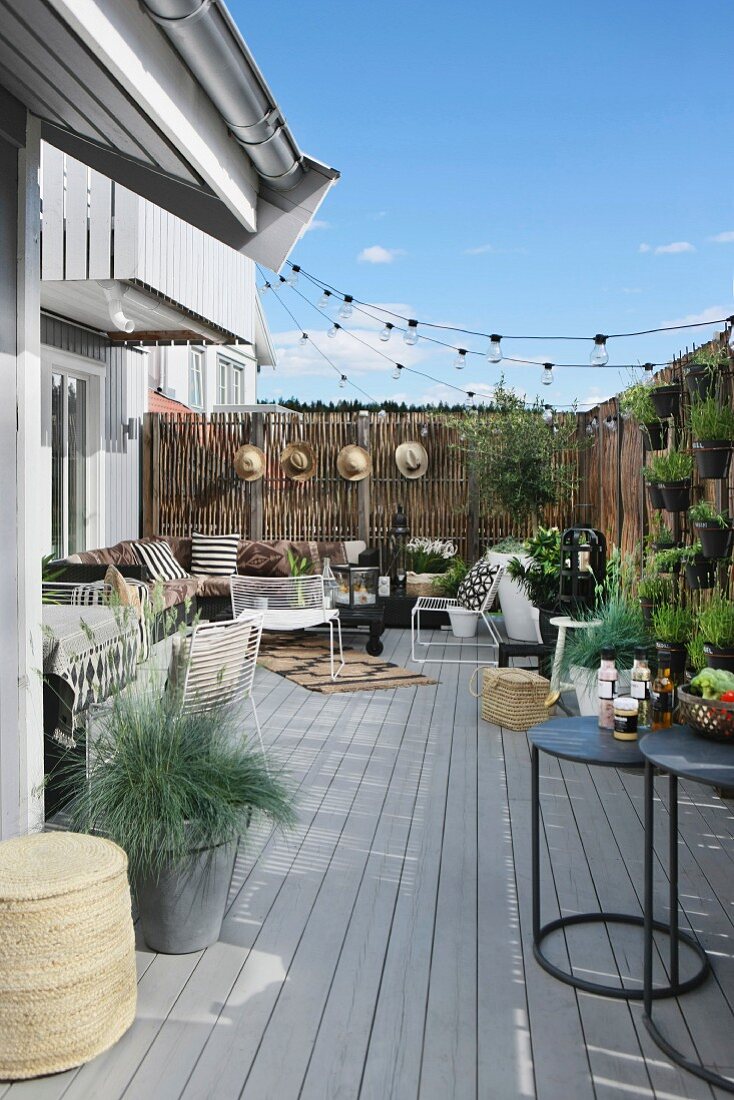 Sommerliche Terrasse mit Lounge-Ecke, Bretterboden und Sichtschutz