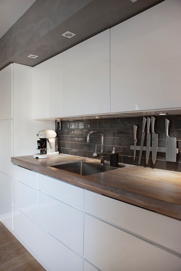 Moderne Küche im Industriestil mit weißen Hochglanzfronten und Arbeitsplatte aus Holz