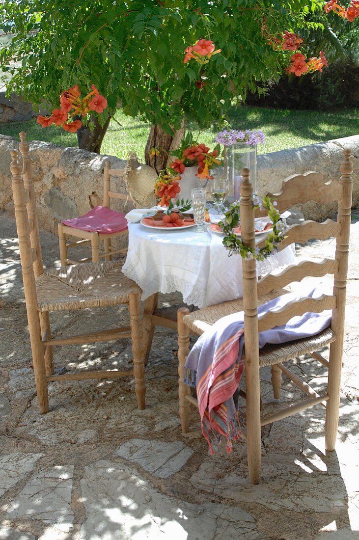 Gedeckter Tisch und Holzstühle in mediterranem Stil auf Terrasse