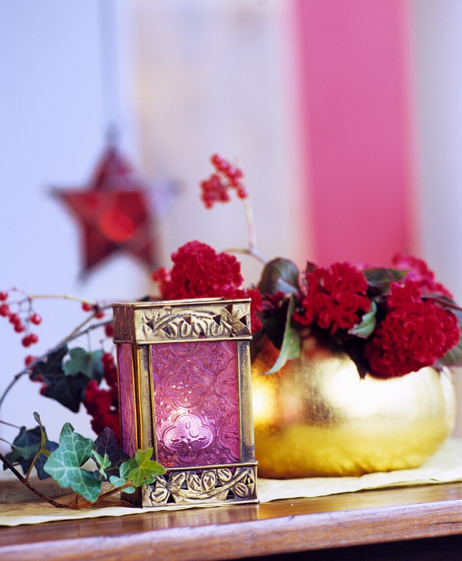 Mini-Laterne mit Teelicht vor Blumenschmuck in goldener Vase